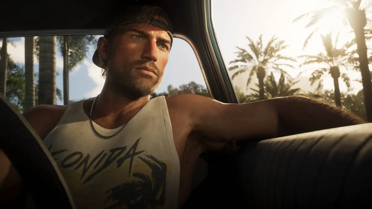 Jason Duval sitting behind the wheel of a car in a white tank top with palm trees outside, from official Grand Theft Auto VI screenshots.